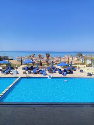 a swimming pool with chairs and umbrellas and the ocean at كازابلانكا ستار in Hurghada