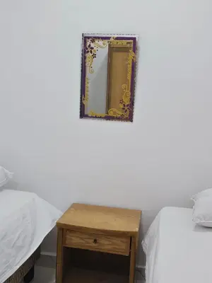 a room with two beds and a table with a mirror at Hatshepsut Apartments Luxor in Luxor