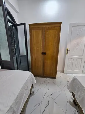 a bedroom with a wooden cabinet and marble floor at Hatshepsut Apartments Luxor in Luxor