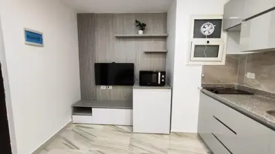 a small kitchen with white cabinets and a microwave at Stylish Sunny Central 1BR in Hurghada
