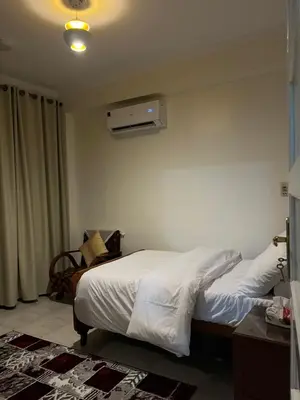 a bedroom with two beds and a air conditioner on the wall at Tut Apartment in Luxor