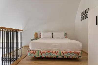 a white bedroom with a bed and a staircase at VESTA - El Gouna Residence in Hurghada