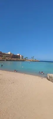 a beach with people swimming in the water at Golden Tiba in Hurghada