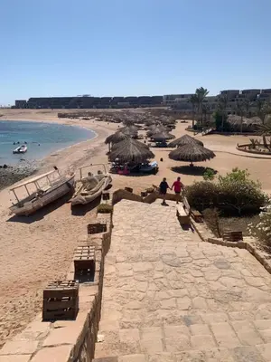 a beach with umbrellas and boats on the sand at 3-Bed Sleeps 6 with Sea View & Free Parking in Hurghada