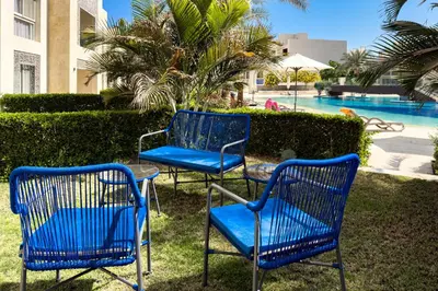 three blue chairs and a table in front of a pool at The Platinum Perch 2BDR Pool View Free Pool & Beach Access in Hurghada