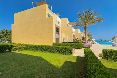 a large yellow house with a palm tree and a yard at The Golden Atrium 3BDR Pool View Free Pool & Beach Access in Hurghada
