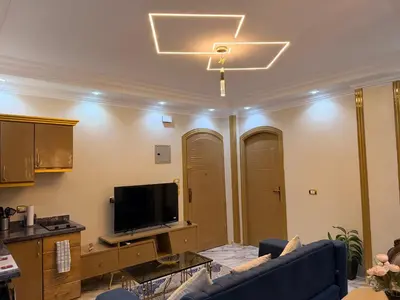 a living room with a ceiling fan and a tv at Oscar Apartment 9 in Luxor