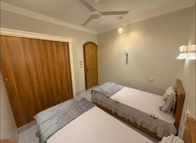 a bedroom with two beds and a door at Oscar Apartment 10 in Luxor