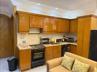 a kitchen with wooden cabinets and a stove top oven at Oscar Apartment 10 in Luxor