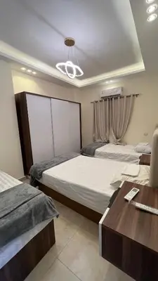 a bedroom with two beds and a wooden table at شقة فندقية امام المارينا 3 غرف 5 سراير in Hurghada