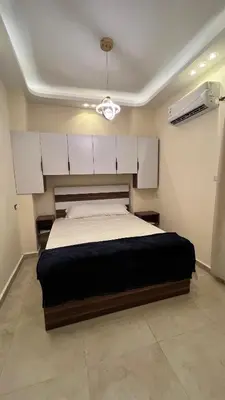 a bedroom with a bed with white cabinets and a ceiling at شقة فندقية امام المارينا 3 غرف 5 سراير in Hurghada