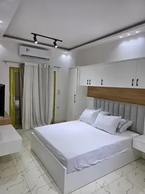 a white bedroom with a large bed with white cabinets at Modern Studio with Pool and Private Beach Access in Hurghada