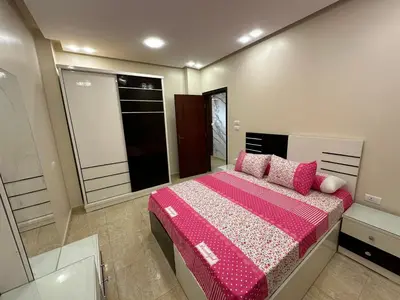 a bedroom with a large bed with pink sheets and pillows at الوفاء امام فندق بيروت in Hurghada