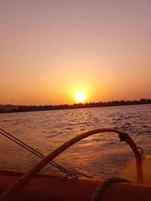 a boat in the water with the sunset in the background at Traditional Felucca Sailing Boat Overnight in Aswan
