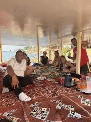 a group of people sitting around a table on the beach at Traditional Felucca Sailing Boat Overnight in Aswan