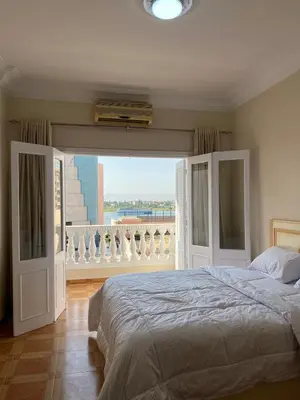 a bedroom with a large bed and a balcony at Nile View Luxe Stay , Walk to Luxor Temple in Luxor