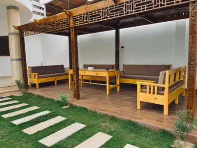 a wooden pergola with benches on a patio at el rabia - private rooms in Luxor
