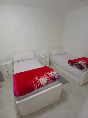 two beds in a white room with red blankets at Arrabia in front of Beirut Hotel in Hurghada