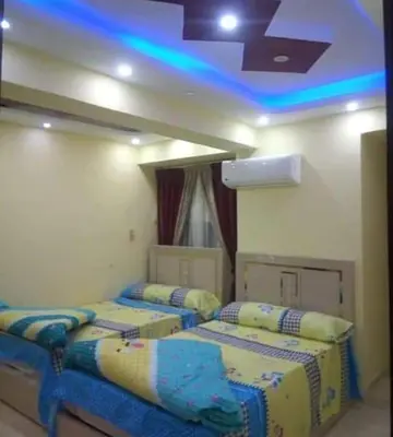two beds in a room with blue lights at الاقصر in Luxor
