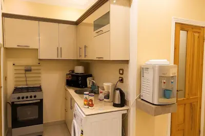 a small kitchen with white cabinets and a microwave at Oscar Apartment 2 in Luxor