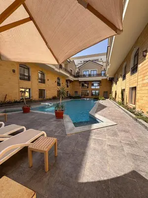 a swimming pool in a building with benches and an umbrella at 201 Aqua Blue Bay in Hurghada
