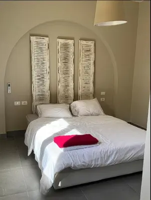 a bedroom with a white bed with a red blanket on it at Spacious outdoor area featuring a swimming pool ! in Hurghada