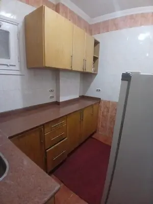 a kitchen with wooden cabinets and a refrigerator at Rent Mubarak 2 in Hurghada