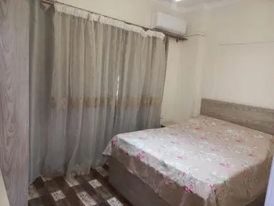 a small bedroom with a bed and a curtain at Apartment compound west sayed Al kawthar in Hurghada