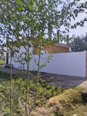 a white fence in front of a house at mariam Garden in Al Aqālitah