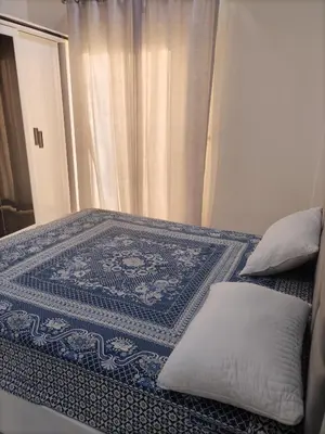 a bed with a blue and white rug on it at mariam Garden in Al Aqālitah