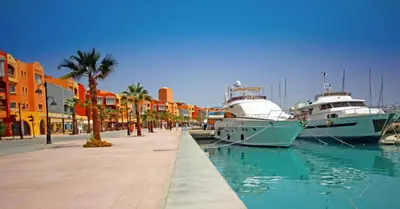 two boats docked at a marina with palm trees and buildings at Luxury Stay in Marina Soma Bay in Hurghada