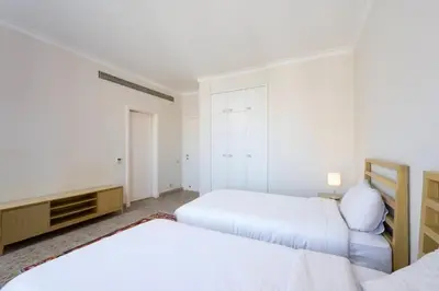 a white bedroom with two beds and a closet at Luxury Stays in Golf Town Houses in Hurghada