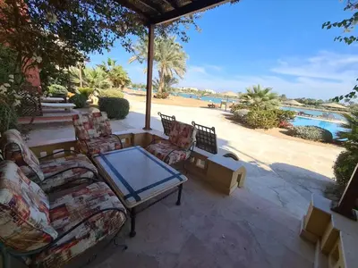 a patio with chairs and a table and a pool at ElGouna west golf 2 bedrooms 2 bathrooms - pool in Hurghada