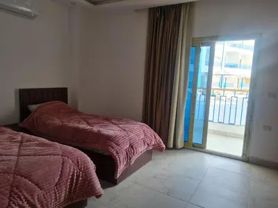 a bedroom with two beds and a sliding glass door at Mirage Bay Resort & Aqua Park in Hurghada