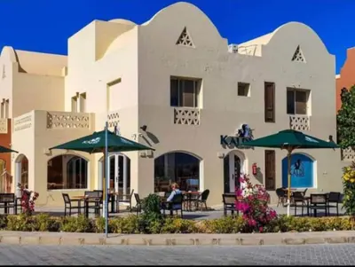a building with tables and umbrellas in front of it at 2BR Makadi heights -cozy Flat in Hurghada