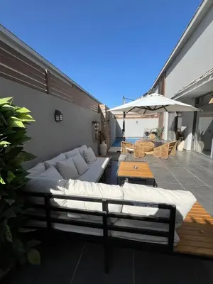 a patio with a couch and tables and an umbrella at Bali - Elgouna Two Bedrooms private Heated pool in Hurghada