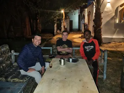a group of three men sitting around a table at Bafana Bafana Nile View Guest House in Aswan