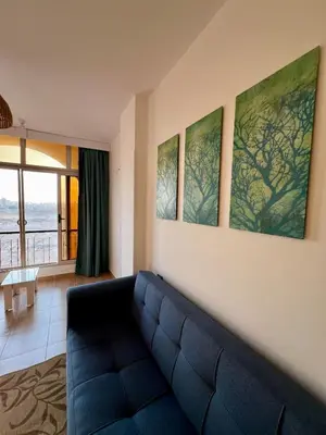 a living room with a blue couch and paintings on the wall at Beautiful desert, mountains, Hurghada skyline view in Hurghada