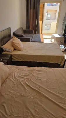 two beds in a room with a couch and a window at florenza-50 in Hurghada