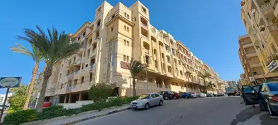 a small car parked in front of a large building at florenza-50 in Hurghada