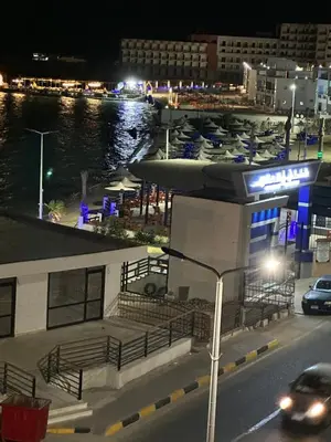 a building with a marina at night with a car at كورنيش القيادات in Hurghada