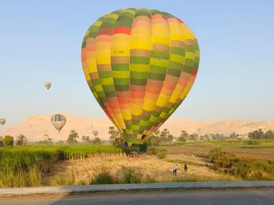 a colorful hot air balloon flying over a field at Pharaohs Rest Luxor in Luxor