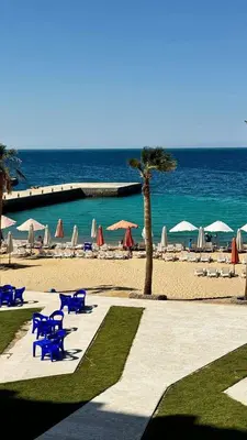 a beach with chairs and umbrellas and the ocean at LA MERA Suite in Hurghada