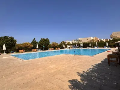 a large swimming pool with chairs and umbrellas at Boho 2-BDR Haven in Makadi Heights - By Kemetland in Hurghada