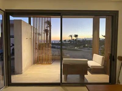 a room with a sliding glass door with a couch and chair at Modern Minimalist Beach & Pool Side Somabay Cabana in Hurghada