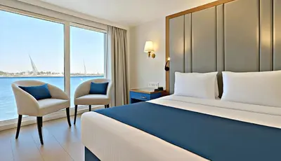 a hotel room with a bed and two chairs at Five-Star Deluxe River Kruz from Aswan to Luxor 3 Nights in Aswān