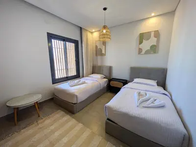 a room with two beds and a table and a window at Spacious 3BR Apartment Glorious Panoramic Seaviews in Hurghada