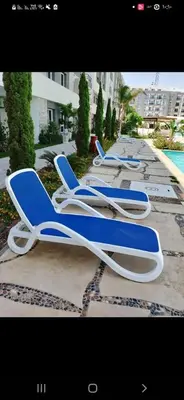 a row of blue and white lounge chairs next to a pool at الغردقه قريه فنادير باى in Hurghada