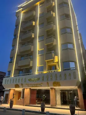 a tall building with people standing in front of it at Grand Cleopatra Hotel-Luxor in Luxor