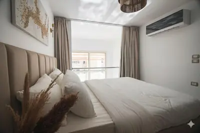 a bedroom with a white bed and a window at Modern Sahl Hasheesh Pool Duplex - Beach & Wi-Fi in Hurghada